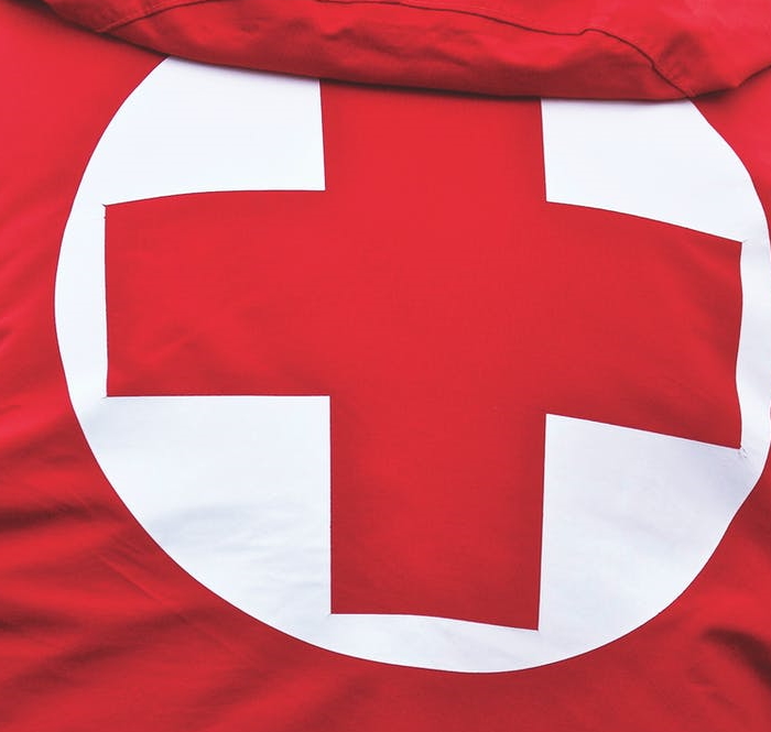 Das Bild zeigt eine Jacke von hinten, auf der ein rotes Kreuz zu sehen ist.